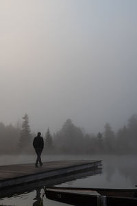 Rear view of man walking on pier at lake