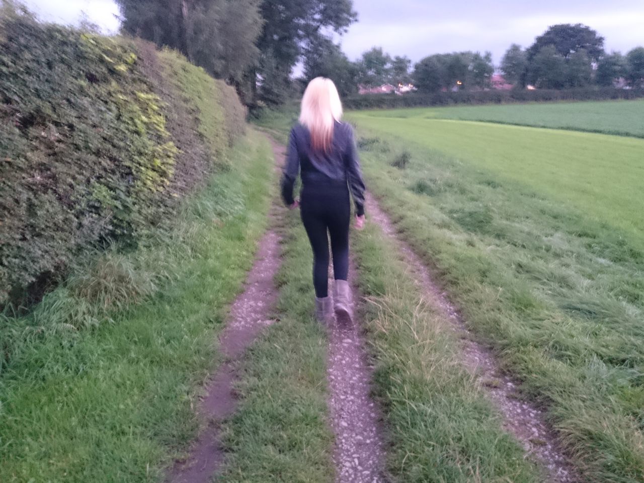 REAR VIEW OF WOMAN STANDING ON GRASSY FIELD