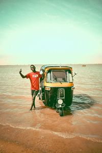 Man standing on boat in sea against sky