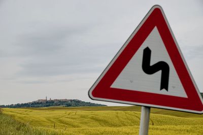 Road sign on field against sky