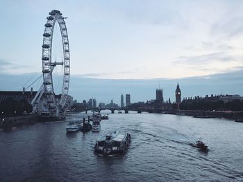 Ferris wheel in city against sky at dusk