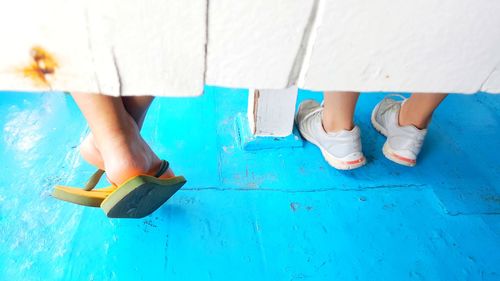 Low section of women wearing blue shoes