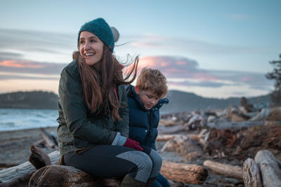 Happy friends sitting on land against sky