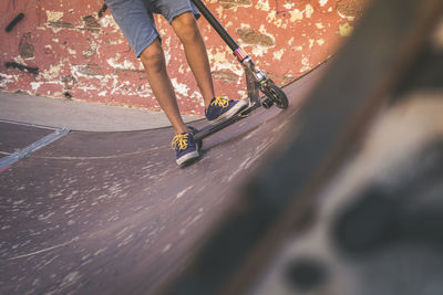 Low section of boy riding push scooter at skateboard park