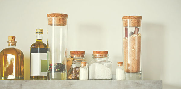 Close-up of glass bottles on table against wall