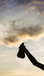 Close-up of silhouette hand holding sun against sky during sunset
