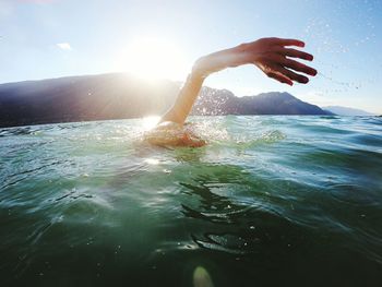 Person in sea against sky on sunny day