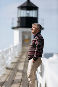 Senior man leaning on the fence looking ahead thoughtfully