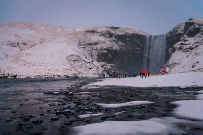 People on snow covered land against sky