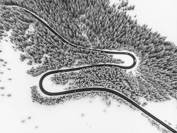 Aerial view shot of winding road amidst snow covered field 