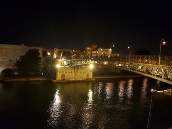 Illuminated bridge over river against sky in city at night