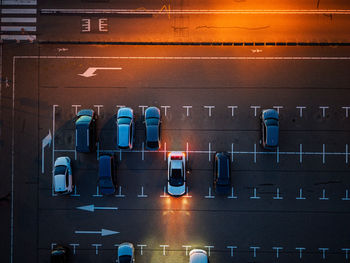 Aerial nighttime view of empty parking lot warm orange streetlights illuminate marked lanes