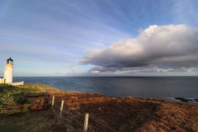 Lighthouse by sea against sky