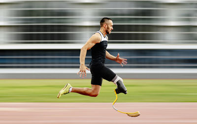 Full length of handicap man running on track