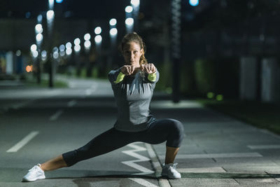 Woman exercising in city at night