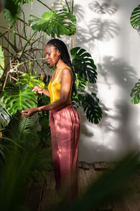 Young woman standing against plants