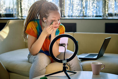 Young woman using mobile phone while sitting on sofa at home