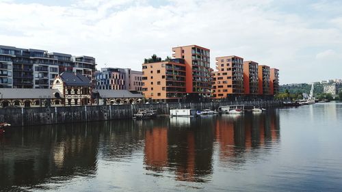 Buildings by river against sky in city