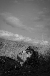 Portrait of woman lying on field against sky