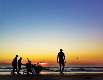 Silhouette of people on beach at sunset