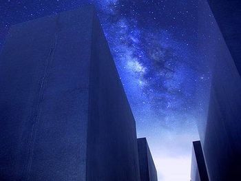 Low angle view of buildings against blue sky at night