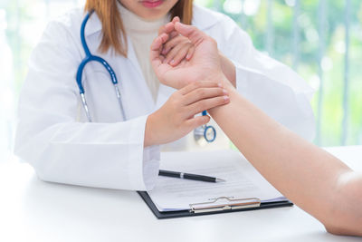 Midsection of woman with hands on table