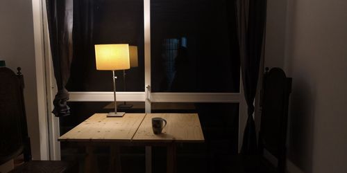 Illuminated electric lamp on table at home