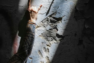 Cropped image of tattooed hand on broken wall