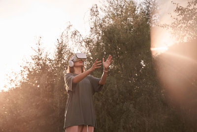 Young woman standing against trees