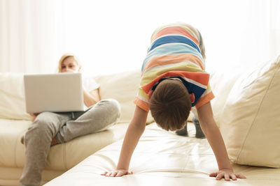 Mother working on laptop while son playing at home