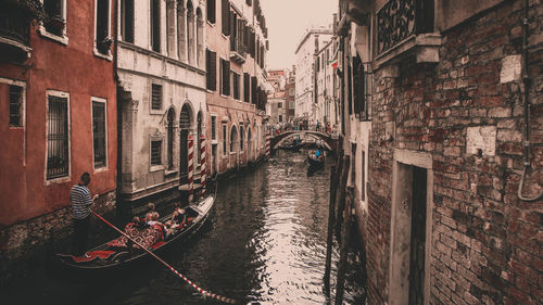 People sailing in gondola amidst buildings