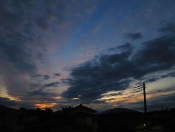 Silhouette houses and buildings against dramatic sky