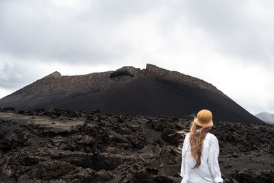 Rear view of woman standing on mountain against sky