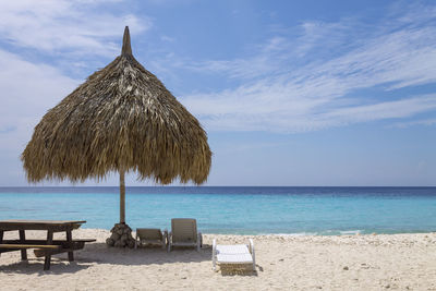 Lounge chairs on beach by sea against sky