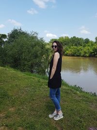 Portrait of young woman standing on tree against sky