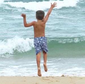 Rear view of boy playing at sea shore