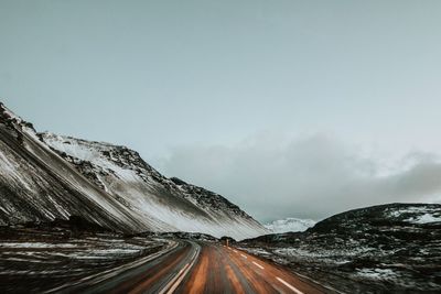 Road amidst snowcapped mountains against sky