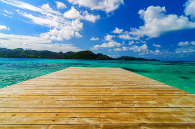 Wooden pier amidst sea against blue sky