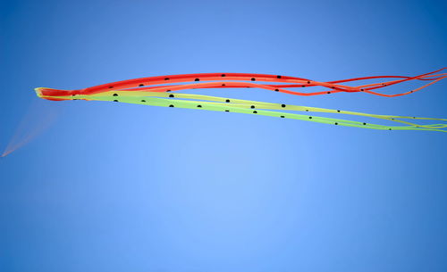 Low angle view of colorful kite flying against clear blue sky