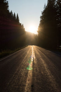 Road amidst trees against sky during sunset