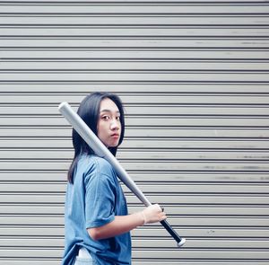 Portrait of young woman standing against wall