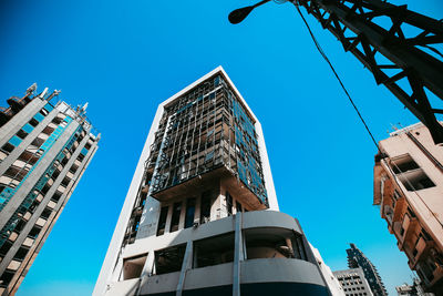 Low angle view of damaged buildings against clear blue sky