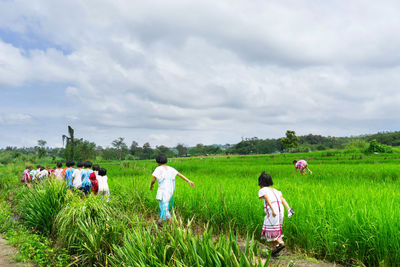 People walking on field against sky