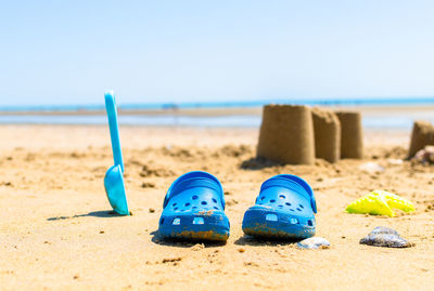 Blue shoes on sand at beach against clear sky