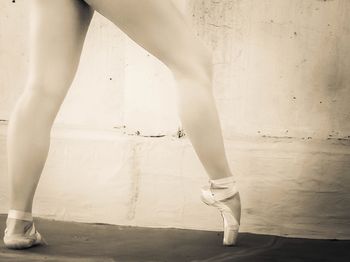 Low section of ballet dancer dancing against wall