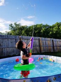 Boy playing in wading pool at backyard