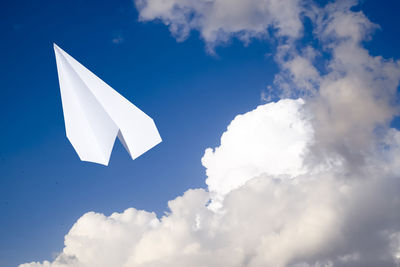 Low angle view of white bird flying against blue sky