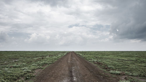 Road amidst field against sky