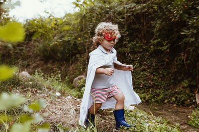 Boy wearing cape walking in forest