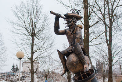 Low angle view of statue against bare trees